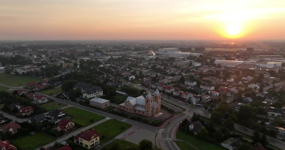 An aerial view of a town during sunset with a warm glow over the buildings and streets
