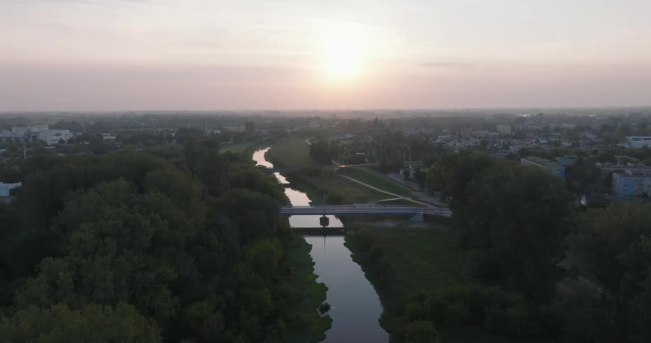 Aerial view of a river dividing an urban city with the sun on the horizon