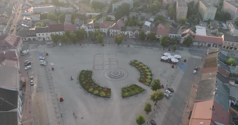 A public square in a citys suburban area surrounded by parked cars and buildings