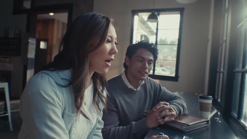 Woman and a man sitting in front of a laptop talking