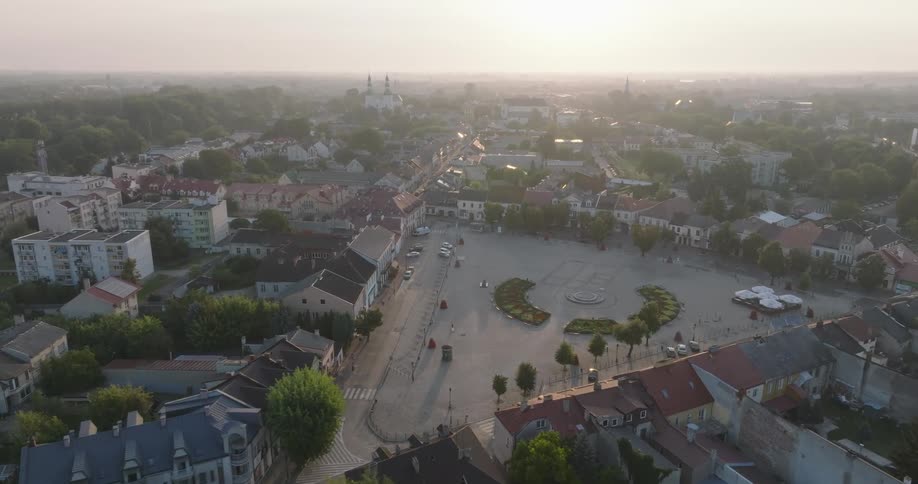 An aerial view of a town square during twilight with buildings surrounding the open space