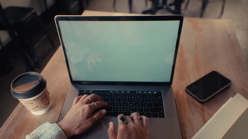 Point of view footage of a person working on a laptop at a wooden table