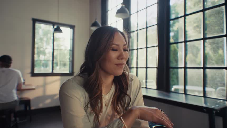 The face of a young woman who is looking down with a thoughtful look and giving a subtle smile