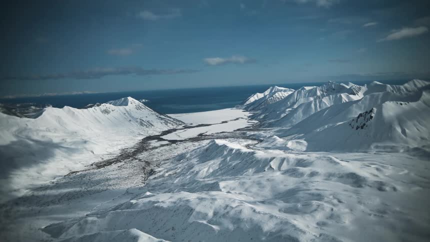 Looking out from a window to snow capped mountain peaks overlooking the ocean