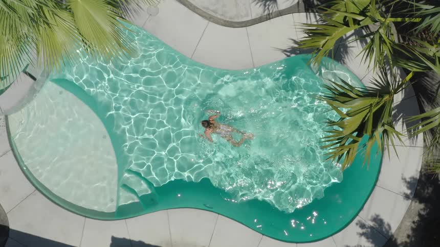 Aerial view of a woman swimming in an outdoor pool