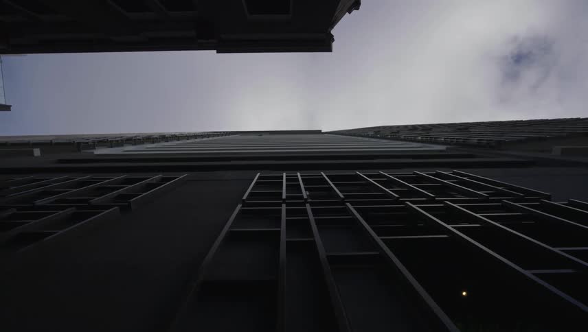 A modern skyscraper stretches into the cloudy sky