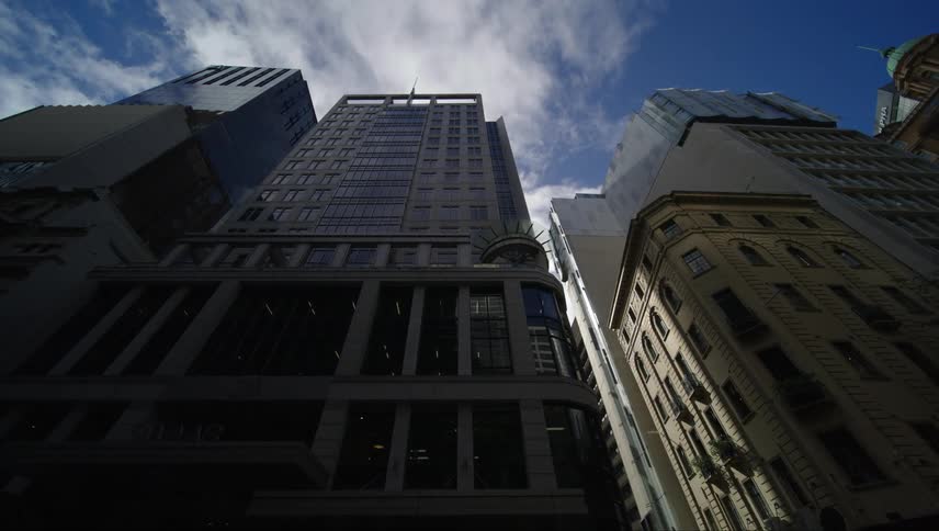 A view looking up towards a clear blue sky framed by several tall buildings