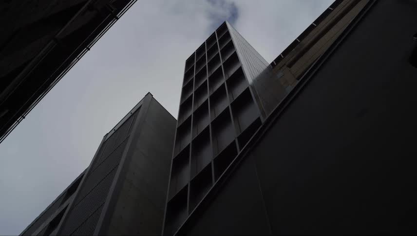 Upward view of exterior architecture of buildings against blue sky with clouds