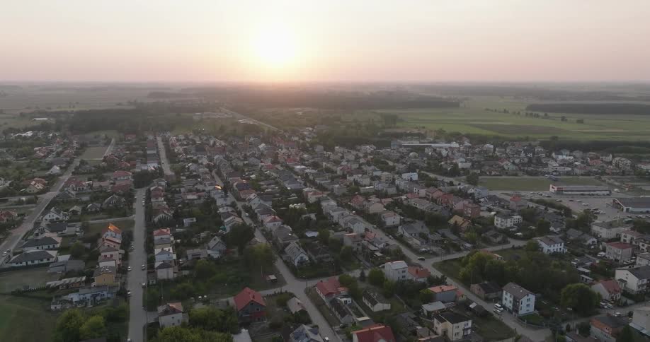 Aerial view of a residential neighborhood with a reddish sun on the horizon