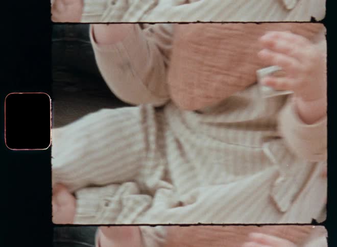 Close up of a female toddler wearing stylish vintage baby clothing in beige colours sitting on the carpet or blanket in front of the father or mother with focus on her hands and legs
