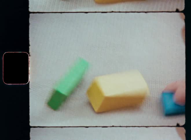 Cute baby playing with educational toys as the little toddler or girl grabs the colorful blue toy blocks with her tiny hands and moves them around on the beige woollen blanket outside on Super-8 film footage