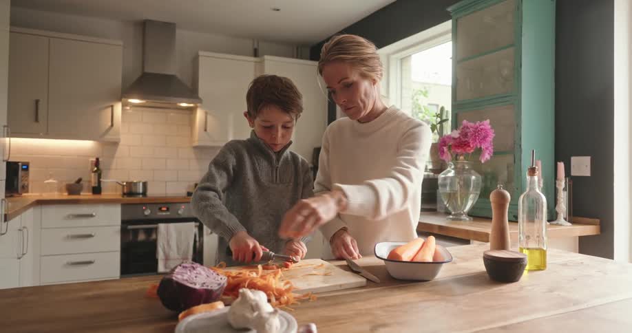 Mother and son in the kitchen peeling a carrot