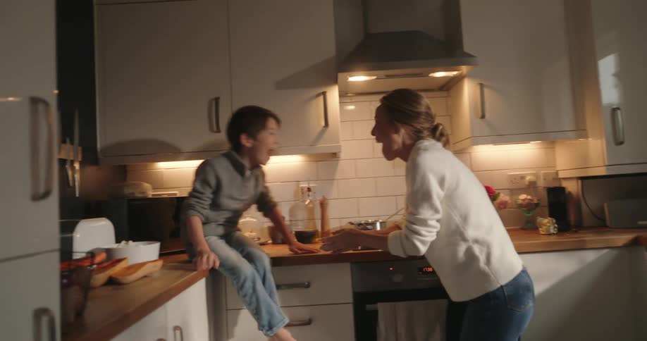 Mother and son cooking and playing together in the kitchen