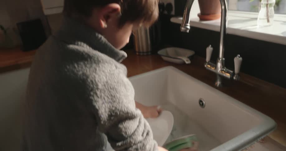 Boy at the kitchen sink washing a dish
