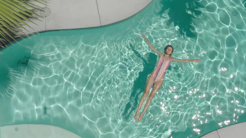 A woman relaxes in the pool on a sunny day