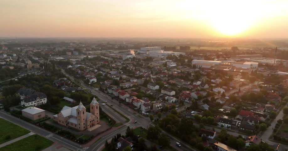 An aerial view of a town during sunset with a warm glow over the buildings and streets