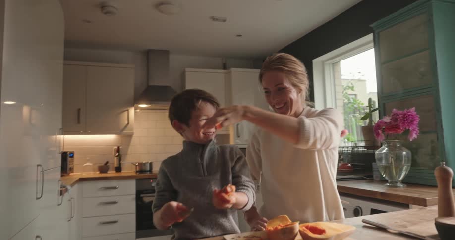 Mother and son playyfully prepare food in the kitchen during the day