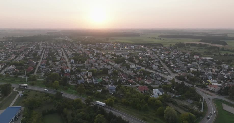 Traffic moves through a suburban area of a city as the sun sits low on the horizon