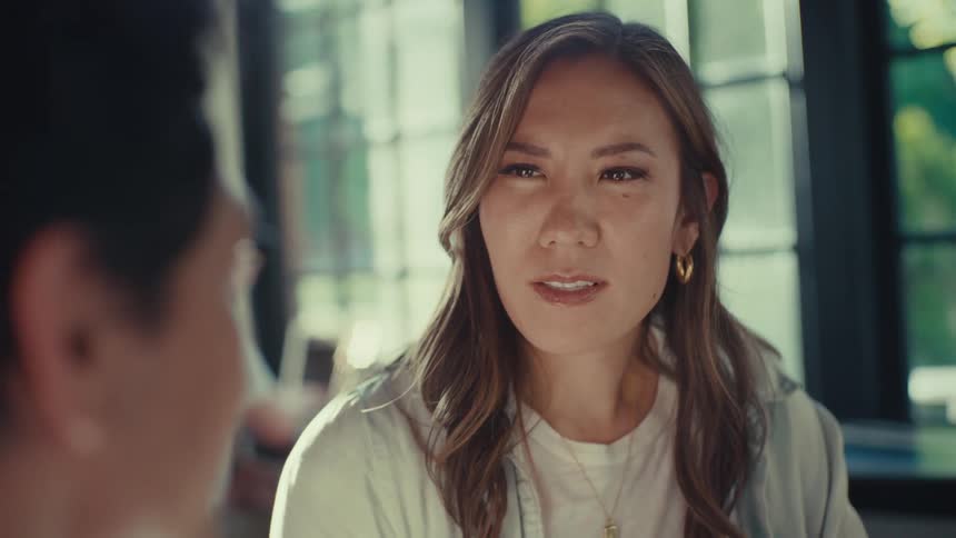 Closeup of a womans face as she listens intently to someone beside her