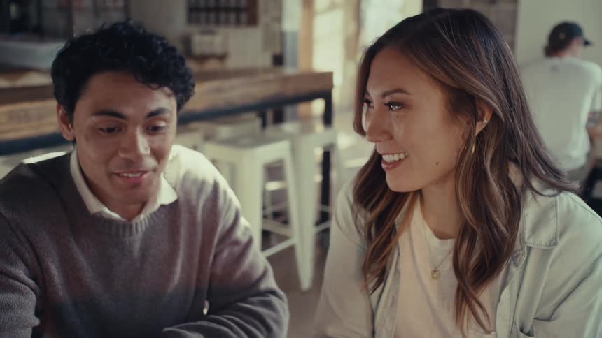 A woman and a man look straight ahead with subtle smiles on their faces and then look at each other and nod their heads and look straight ahead again