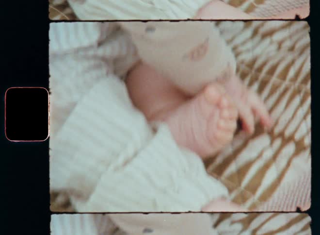 Closeup of a babys hands and feet resting on patterned picnic blanket touching the soft fabric and feeling the sensory impression while experiencing or developing the tactile sense or sense of touch captured on vintage Super 8mm film