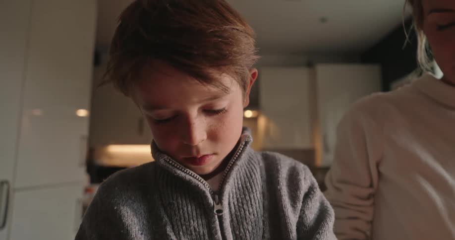 Boy taking seeds from a fruit next to his mother