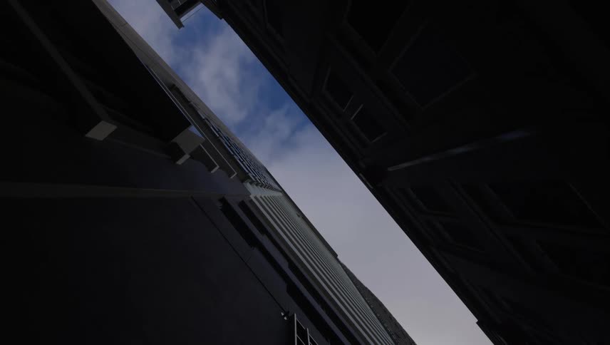 View upwards between buildings and the cloudy blue sky