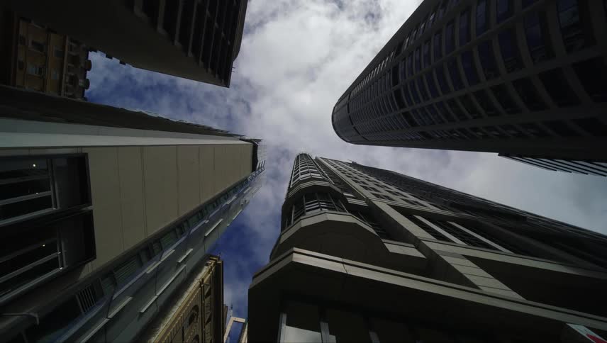Upward view of tall buildings against a cloudy blue sky