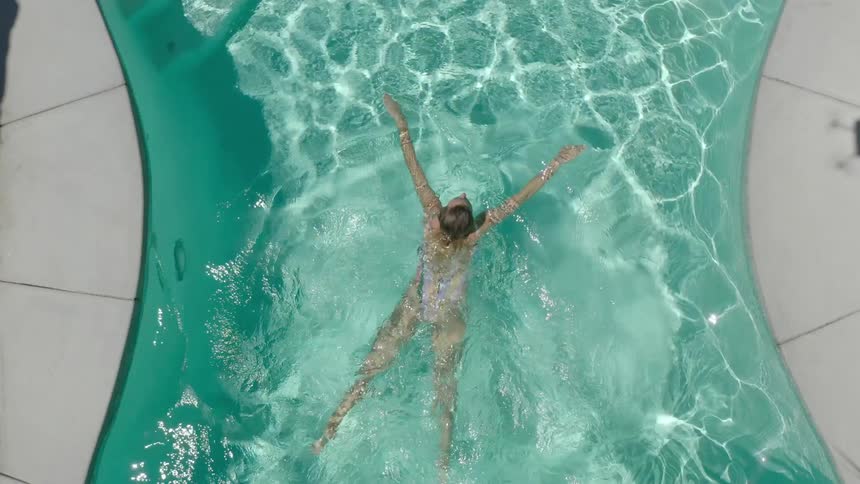 A woman swimming in a pool with clear turquoise water