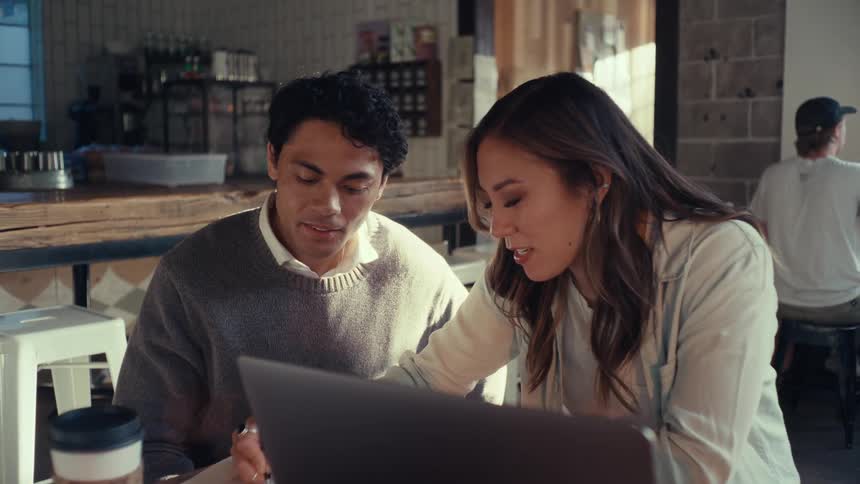 Two people working together on a table in a coffee shop