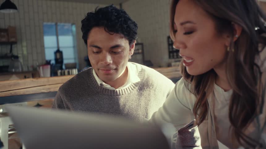 Man and woman sitting in front of a laptop talking to each other