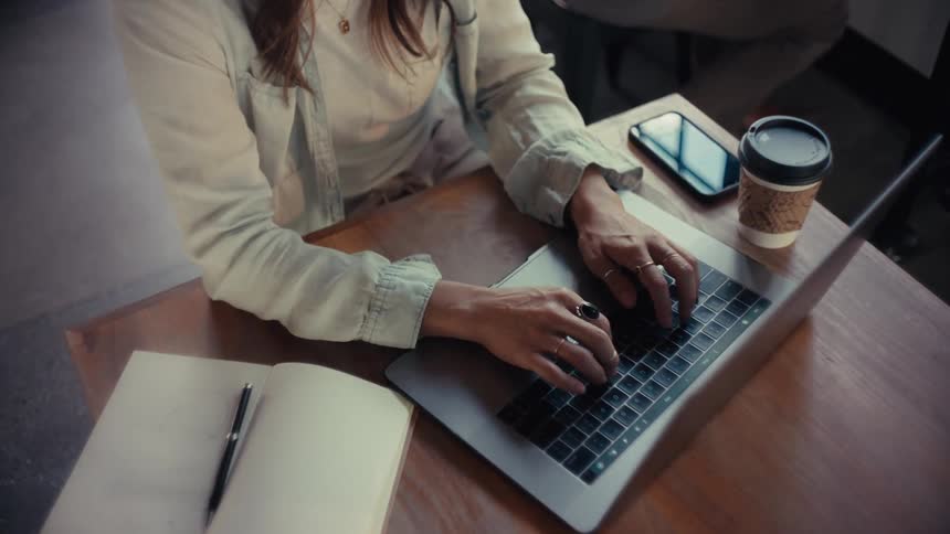 A woman in an office types on a laptop computer