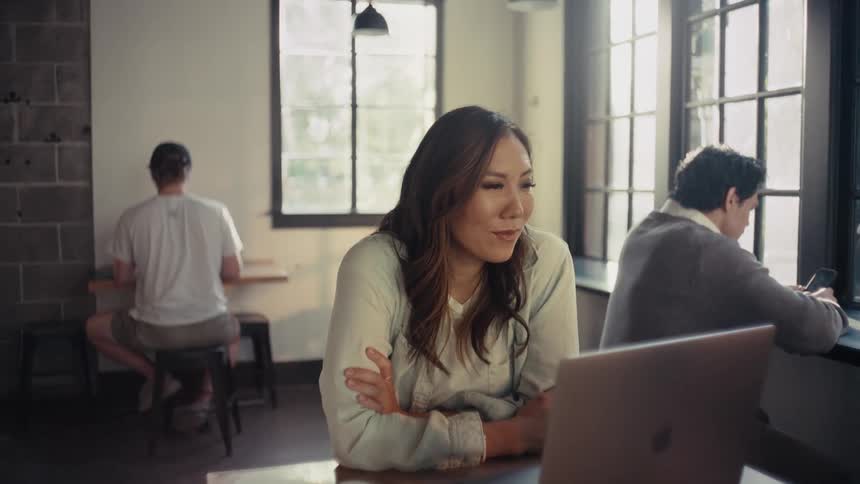 Woman with happy facial expression sitting at a table in front of laptop