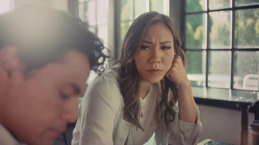 Woman sitting next to a man and looking at him with a strange face