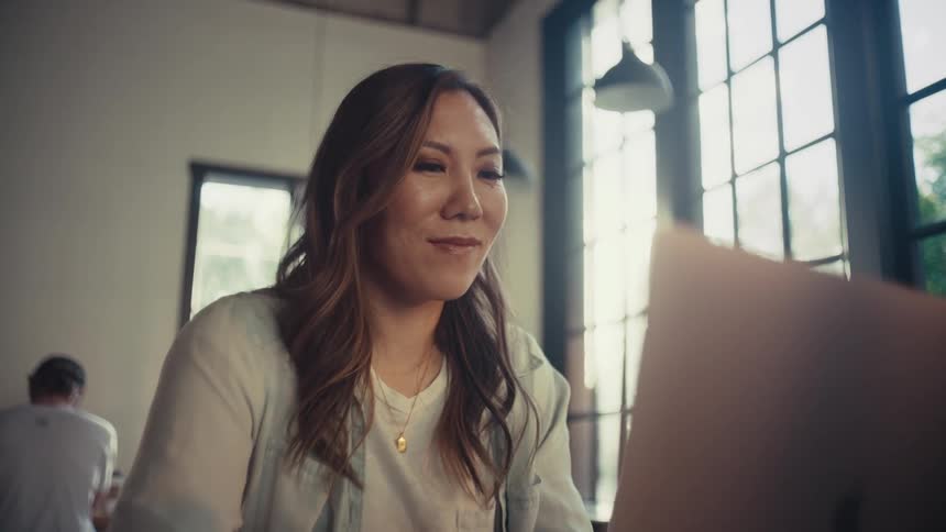 Woman sitting with happy facial expression while working on a laptop