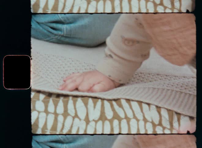 Closeup of a baby’s hands crawling on the floor or ground that is learning how to move on its own while resting on blanket or carpet made of patterned fabric captured on vintage film