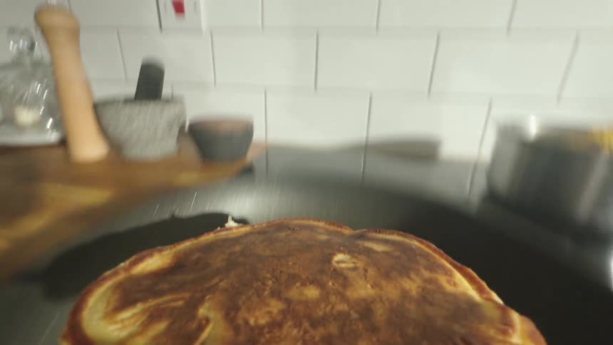 Point of view of a spatula flipping a pancake in a frying pan
