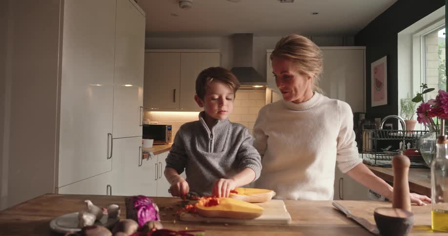 Mother and son together in the kitchen cooking with a  a butternut squash