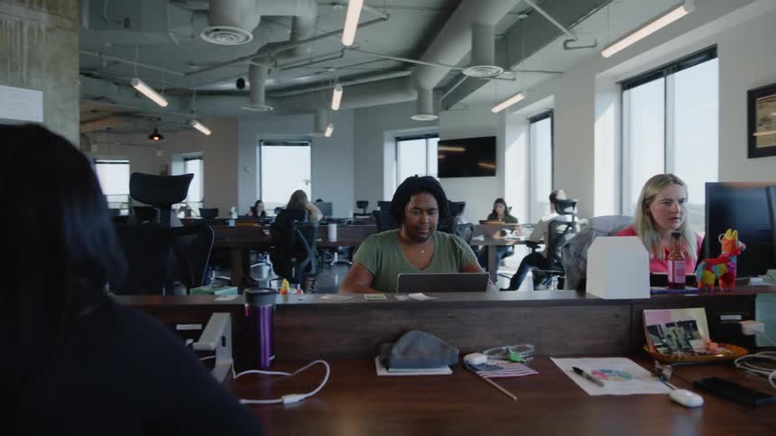 Several people in an office sitting are working with electronic devices that are on the table