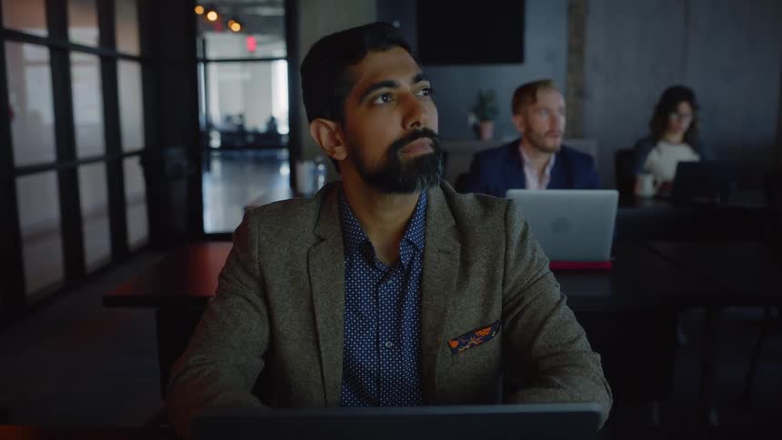 Close up of a bearded young man with a laptop attending a meeting at the office