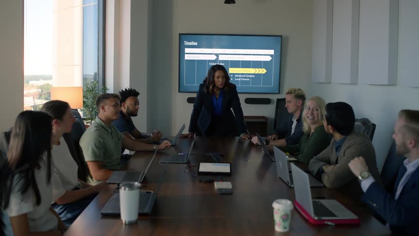 Group of excited people in an office meeting listening to their coworker