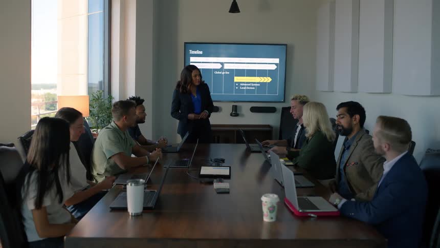 Woman standing presenting and talking to others in a meeting in an office room