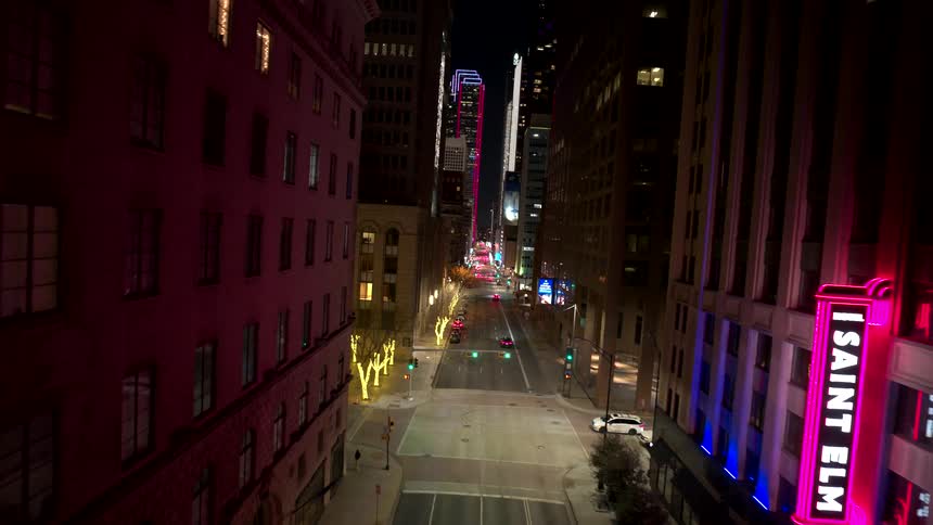 Street of a metropolis with vehicle traffic and buildings illuminated at night