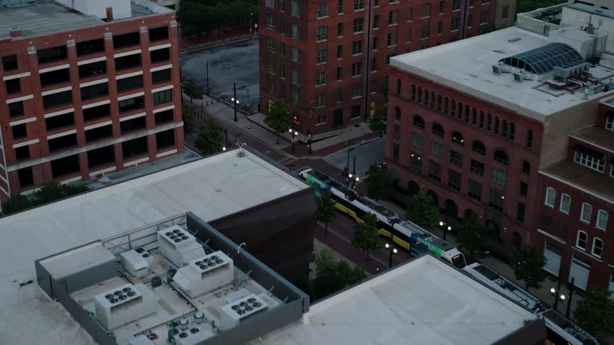Aerial view of a city at dusk capturing the tops of several buildings and a street with a moving tram