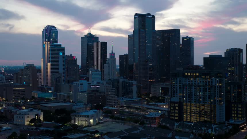 A sprawling cityscape at dusk with the last rays of sunlight casting a pink hue on the clouds