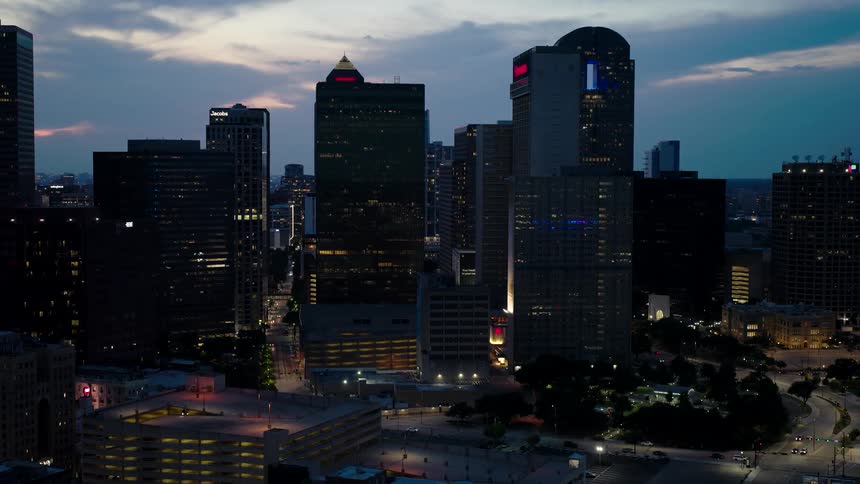 A metropolitan city with several tall buildings and the lights on at dusk