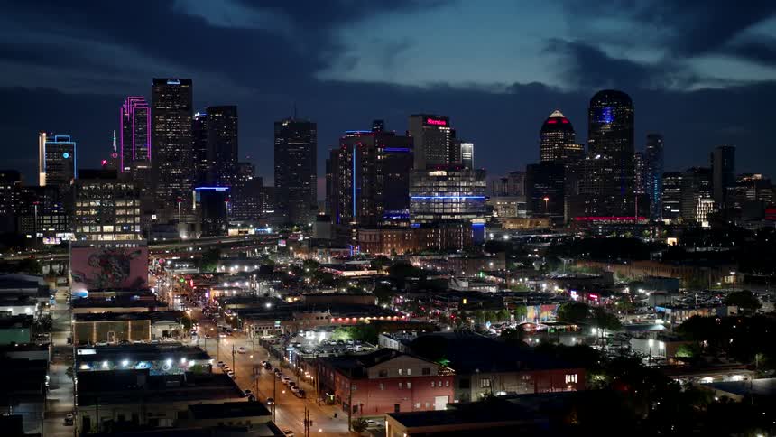 Aerial panorama of a residential neighborhood and illuminated skyscrapers in the background seen at night