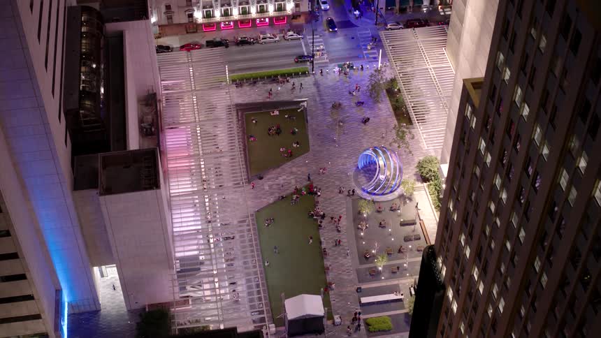 Aerial night view of an urban plaza with a blue illuminated spherical structure at the center