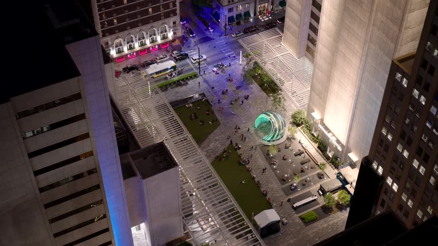 Pedestrians walk in the area between downtown skyscrapers at night
