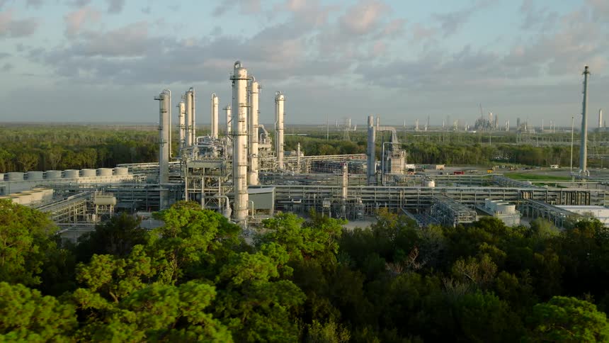 Aerial view on a cloudy morning of a factory and refinery surrounded by trees